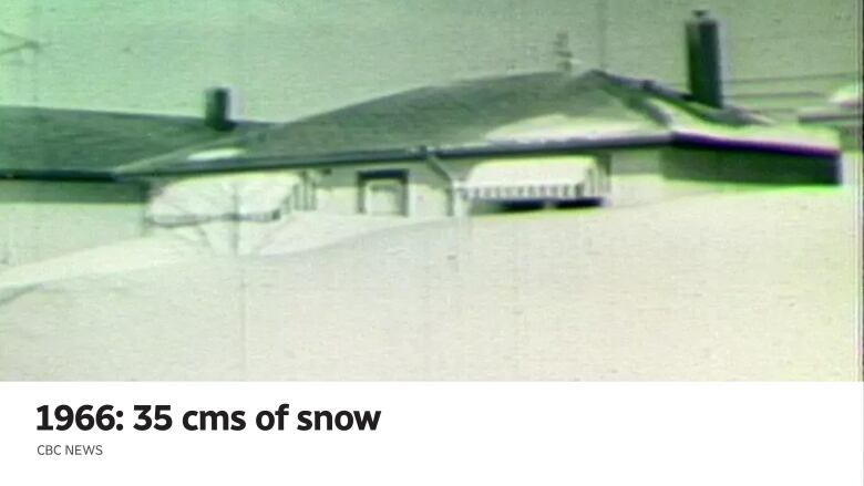 The top of a house is seen behind a snowdrift