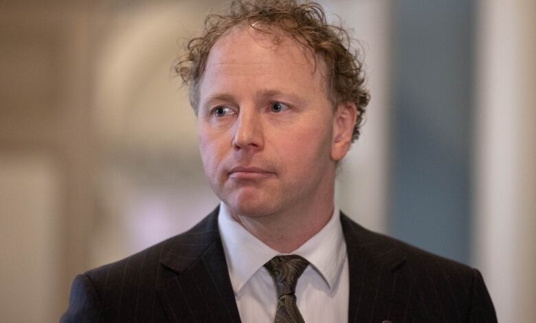 A headshot of a man wearing a suit.