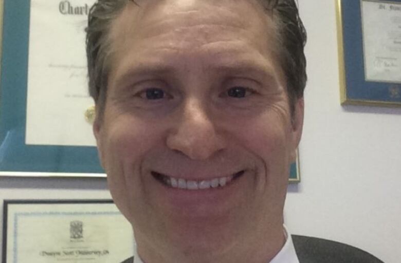 Man in white business shirt and tie smiles into camera.