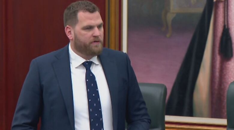 A man has a neutral expression while speaking in the Alberta legislature.