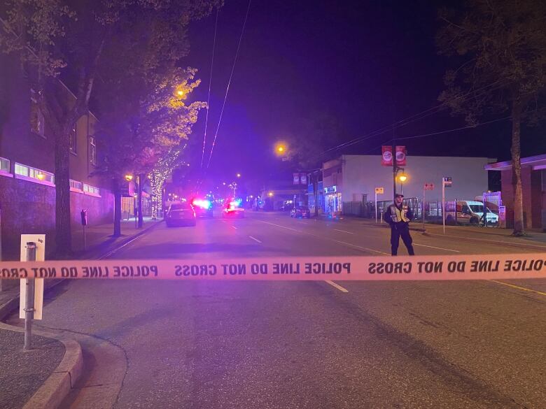 Yellow police tape blocks off a four-lane road in Vancouver at night.