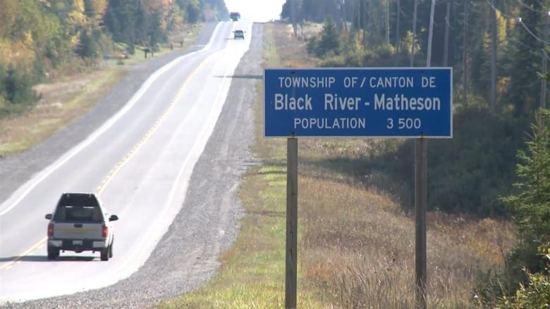 A highway with a sign indicating the town's population.