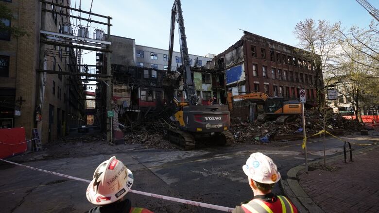 Two firefighters look at a derelict building.