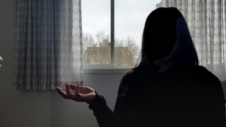 A silhouette of a woman in front of a window.