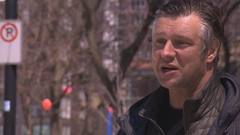 A close-up image of a man speaking outside. 