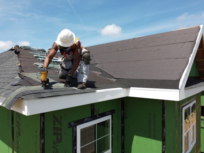 A construction worker does roofing on top of a newly built home.