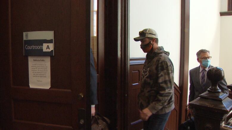 A man wearing a medical mask walks into a courtroom.