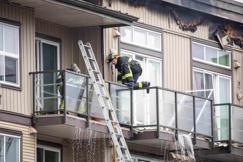 Fire crews on a lift into a burned apartment building.