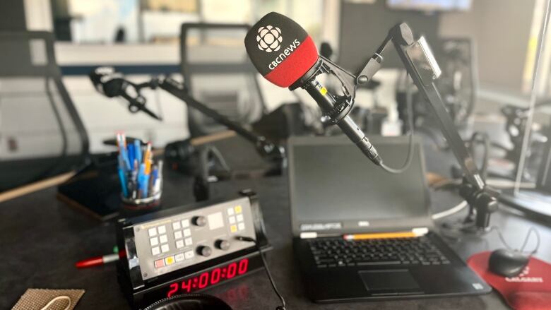 A CBC microphone, laptop and recording gear inside a studio.