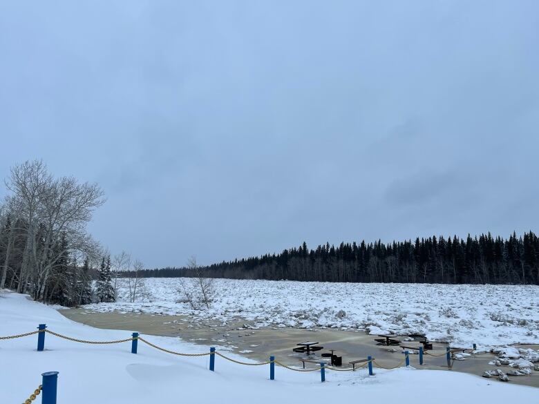 Ice-choked river, snow on banks, picnic table underwater.