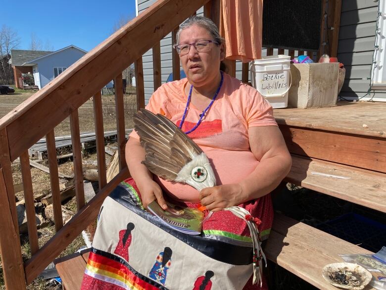 An Indigenous woman wearing a ribbon skirt and an eagle wing.