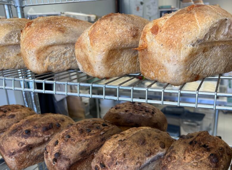 Loaves of bread sit on wire shelves.