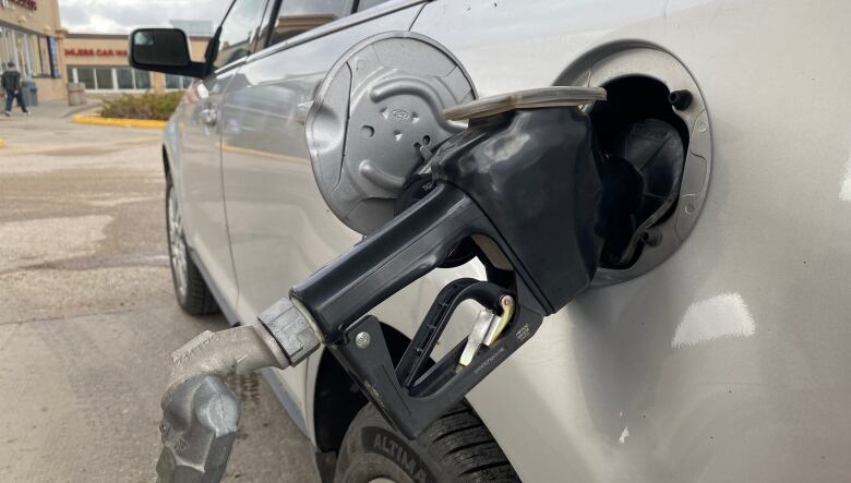 Gas pump seen beside a car. 