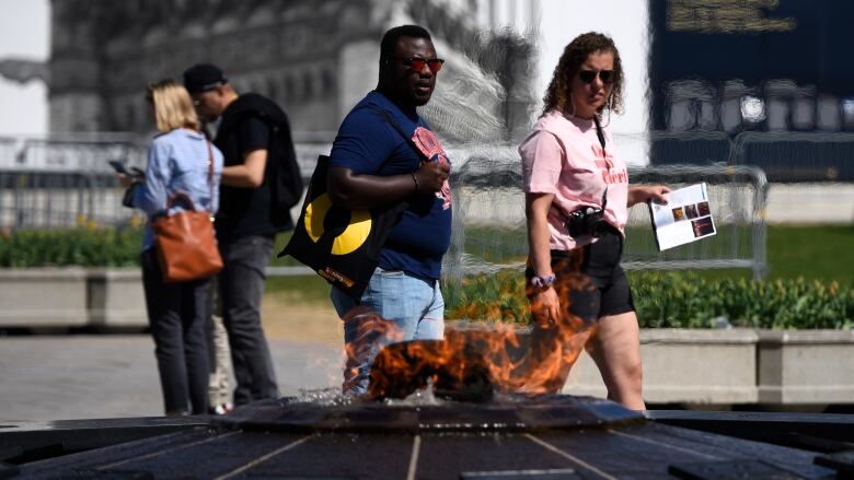 Two people walk past a commemorative fire.