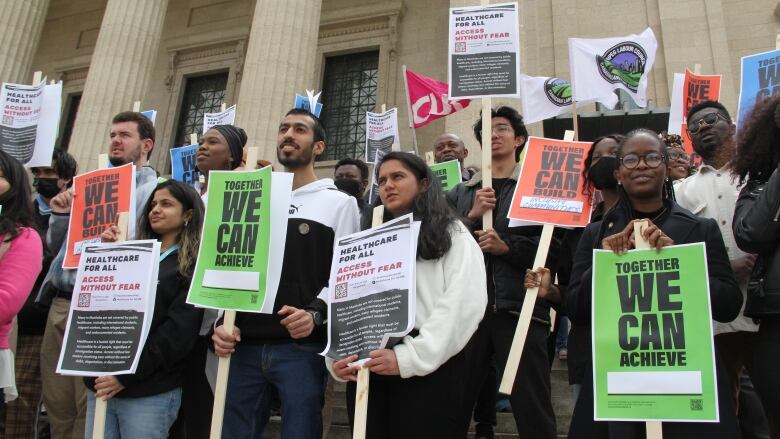 Students are seen holding protest signs reading 'Together we can achieve' during an outdoor demonstration.