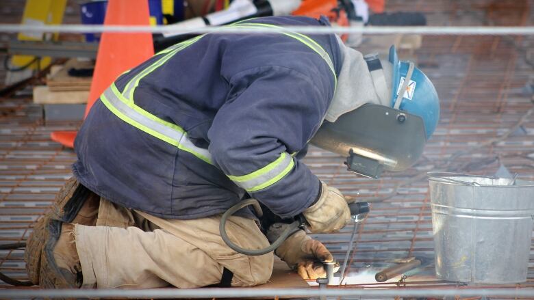 A person is shown kneeling and welding together pieces of rebar.