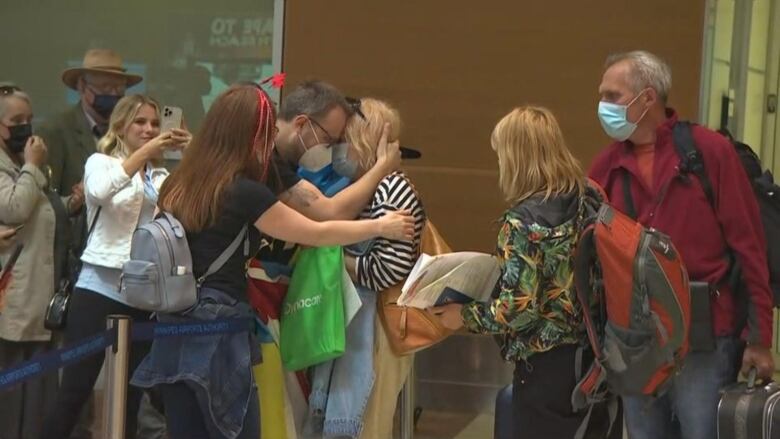 People hug at an airport.