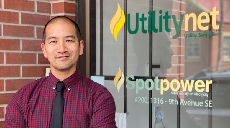 A man posing in front of a sign that says UtilityNet / Spotpower