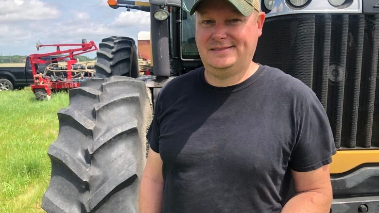 A man stands in front of  a tractor