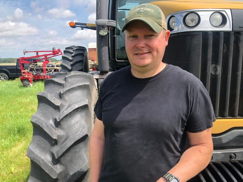 A man stands in front of  a tractor