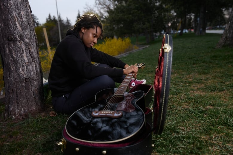 Lia Mighty takes her guitar out of its case. The Black musician from Montreal has faced racial slurs within the LGBTQ+ community.