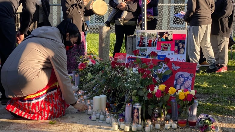 A person puts down a candle at a vigil.