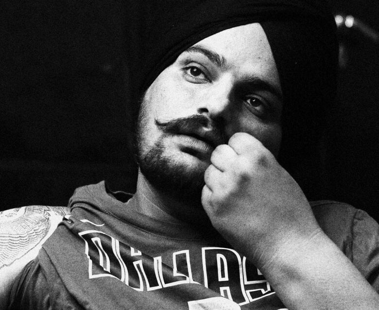 A black and white photo of rapper Sidhu Moose Wala. He is wearing a turban and a Dallas Mavericks basketball shirt.