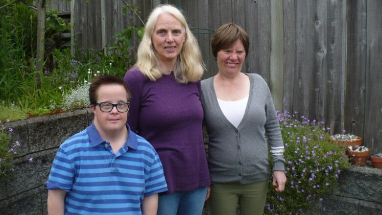 Three woman are shown standing together in a garden. Amy McMillan, left, Sandra Marquis, centre, and her daughter Camille all believed that a third of units in a new affordable housing development in Ladysmith, B.C., would be prioritized for people with developmental and intellectual disabilities.