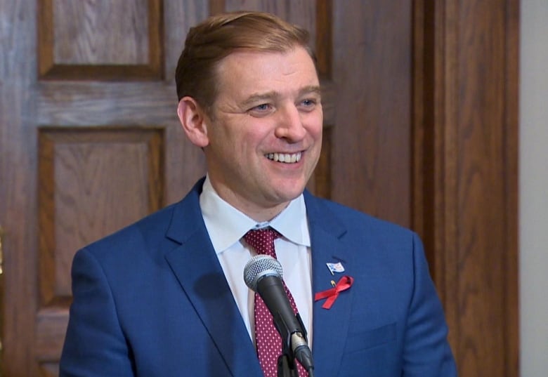 Andrew Furey smiles as he speaks with reporters outside the House of Assembly. 