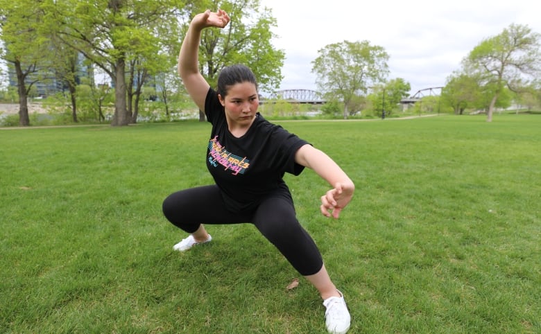 Banin Arjmand squats with an outstretched leg and arms in a martial arts pose.