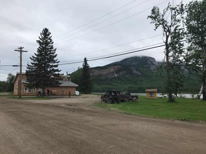 Dirt road with building ahead and mountain in background. 