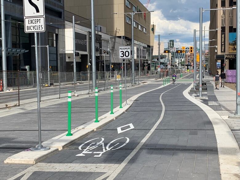 A street is shown with bike lanes, a one-way single-lane roadway and LRT tracks.