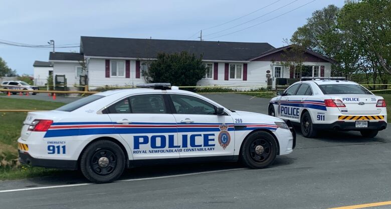 Two police cars parked outside of a home. 