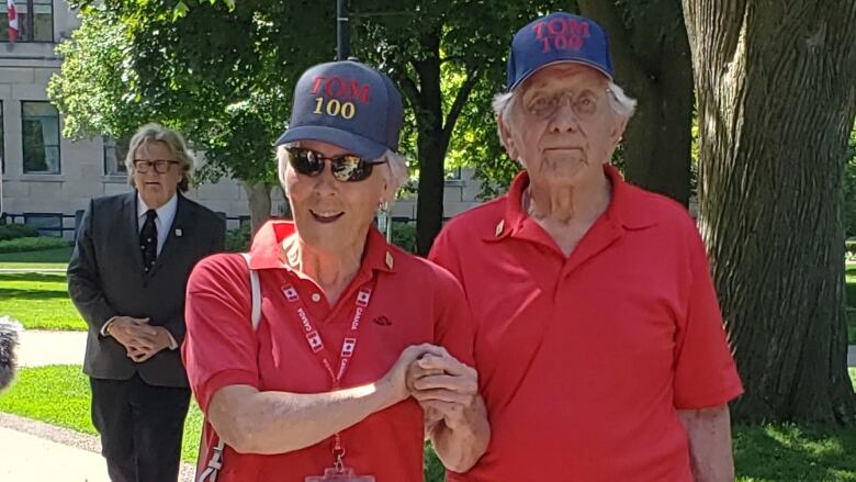 100-year-old Tom Hennessy is walking with his wife on the street. 