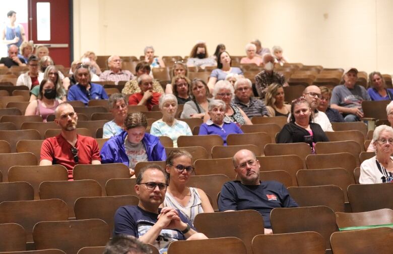 People seated around an auditorium at Harrison Trimble High School in Moncton.