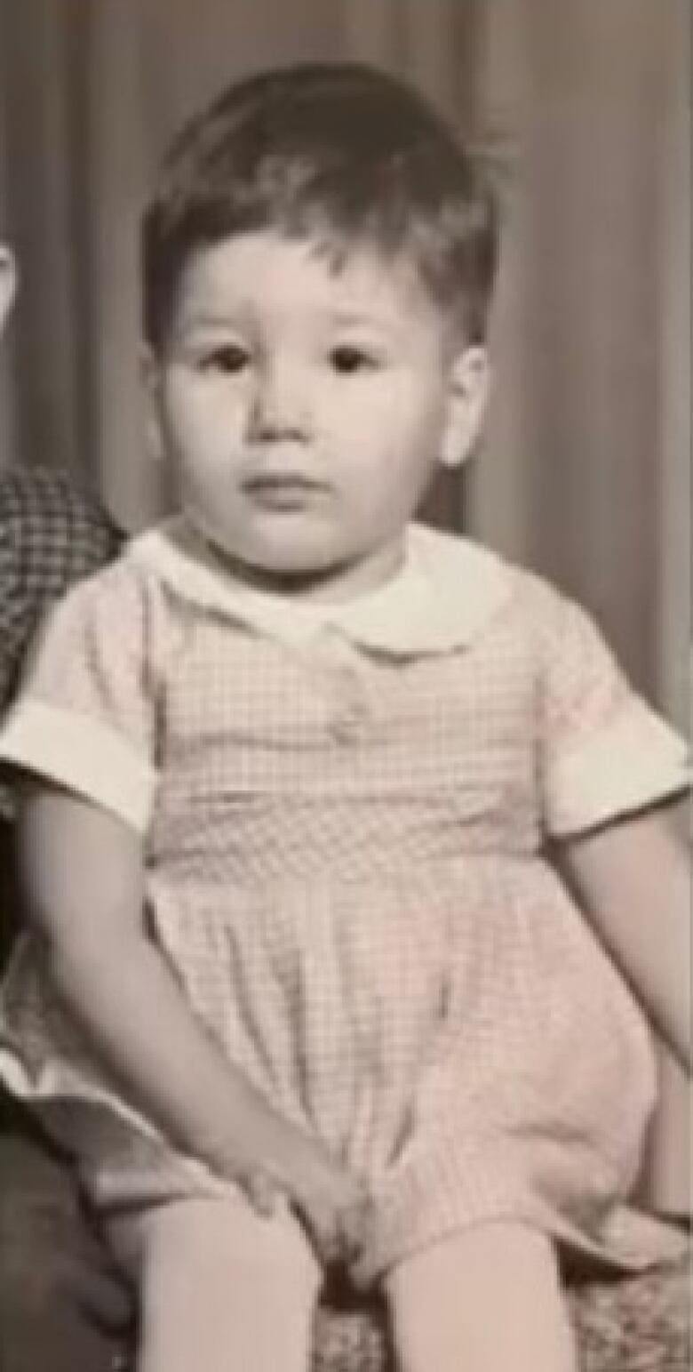 Black and white photo of 60's scoop survivor Minda Burley. Shows Burly when she was an infant with short black hair and wearing a dress. 