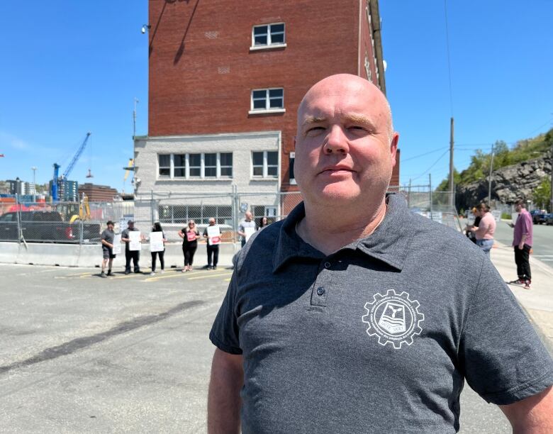 A man stands in front of about a dozen protesters. 