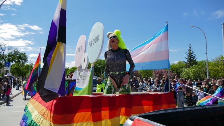 A drag queen smiles on a float.