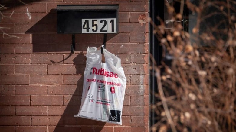 A bag of flyers hangs from a mailbox.