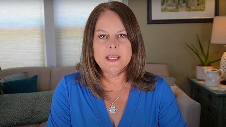 A woman wearing a blue shirt faces the camera.