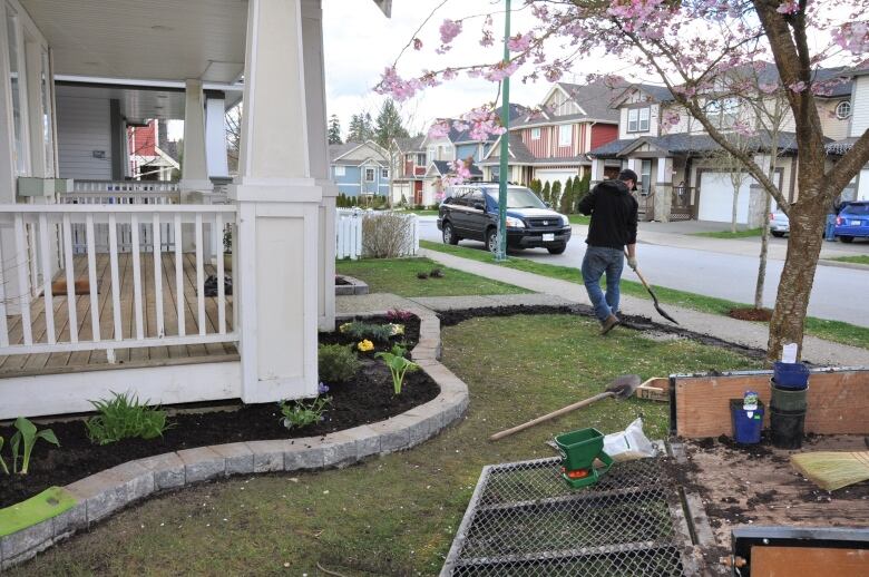 A man holds a shovel as he landscapes his front yard.