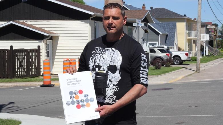 A man who was evacuated holds a brochure that provides information on the assistance available to the evacuees.