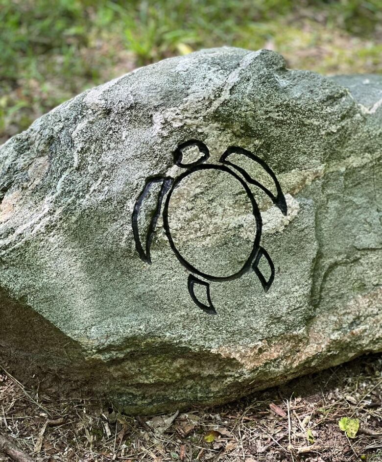 A large stone has a turtle drawn on it.