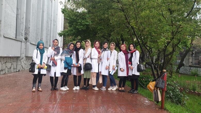 A group of female students wearing white lab coats pose together. 