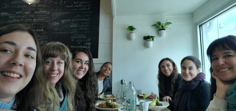 A group of seven women sit around a restaurant table. 