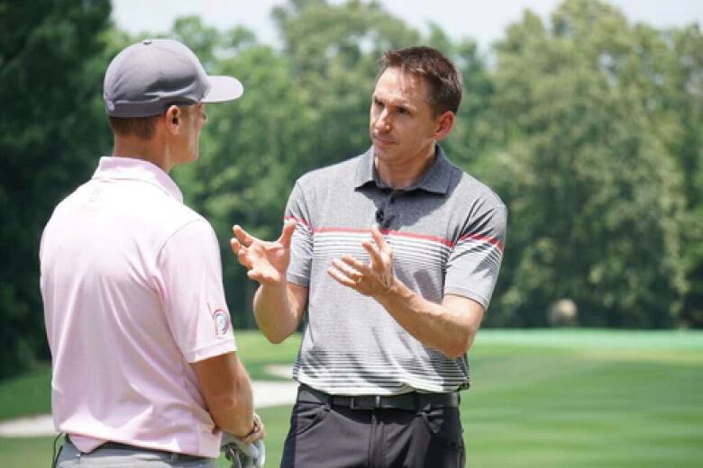 Two men chat on a golf green.