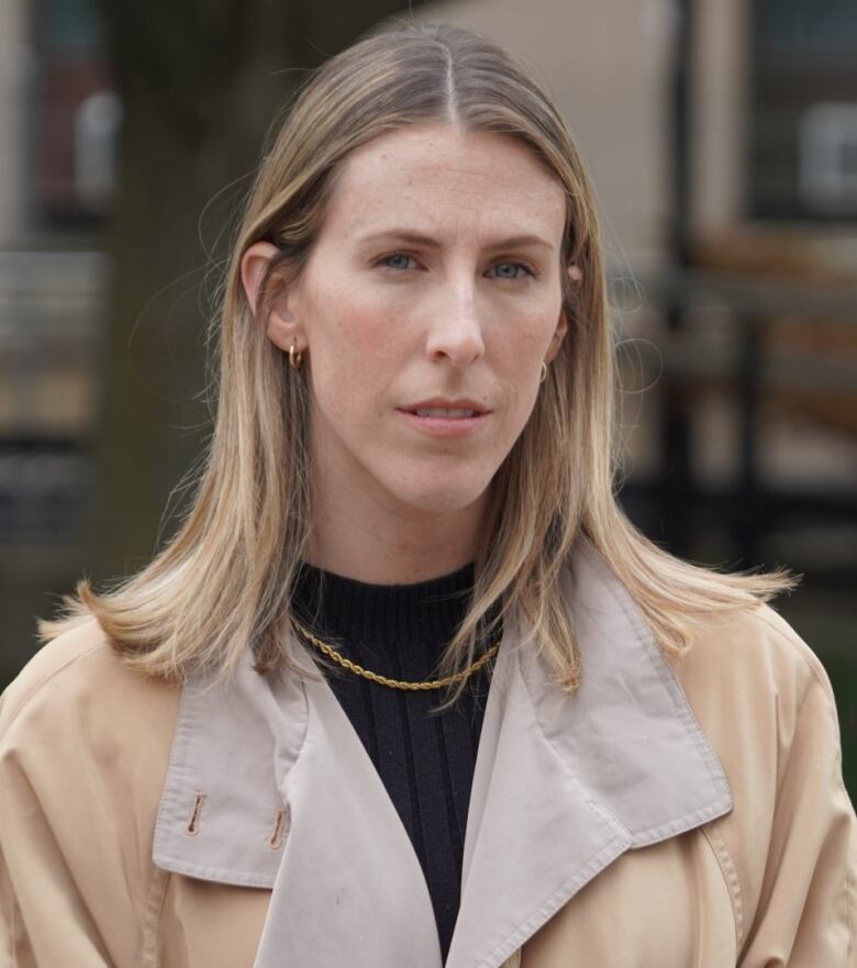 Medium shot of young woman standing outside.