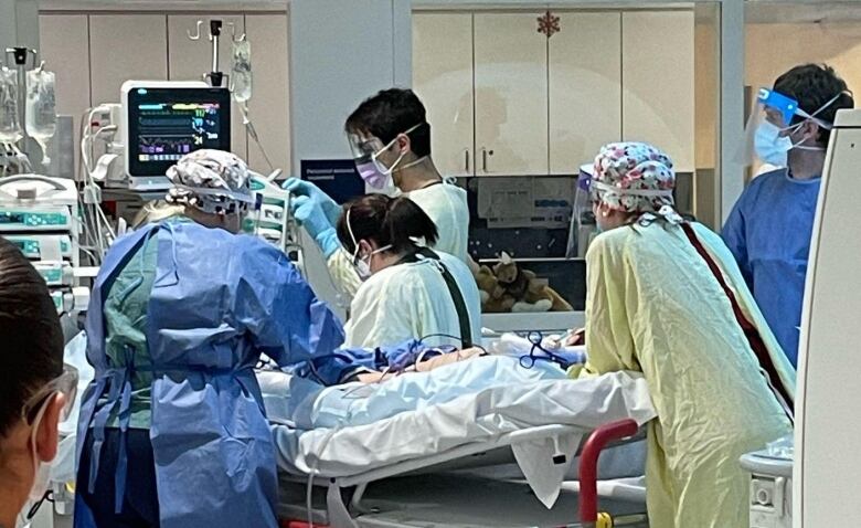 A medical team surrounds a boy on an emergency room bed.