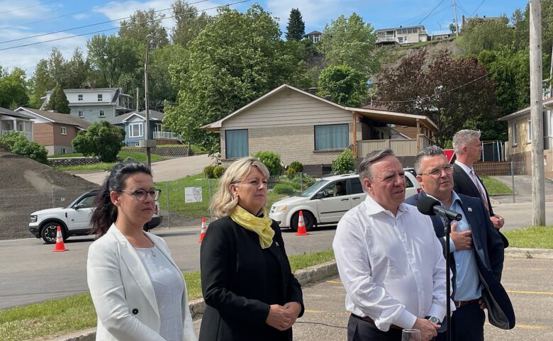 Politicians stand shoulder to shoulder at an outdoor news conference.