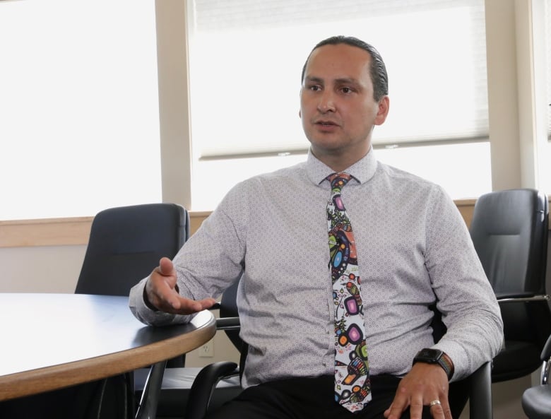 Chief Cadmus Delorme sits in a chair wearing a white shirt and colourful tie as he speaks with CBC News.